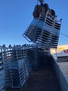 Crane picking up racks of metal frameworks for scrap recycling