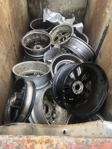 Pile of scrap metal alloy wheels in a skip